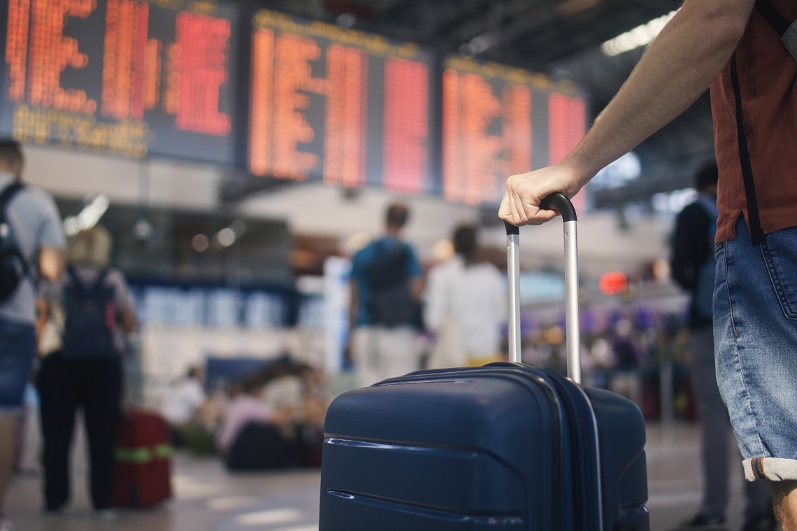 Una persona sostiene una maleta de viaje en una estación de tren